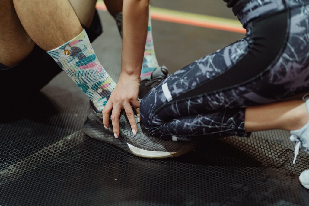 Athletes adjusting sneakers on gym floor, emphasizing sports preparation and team support.